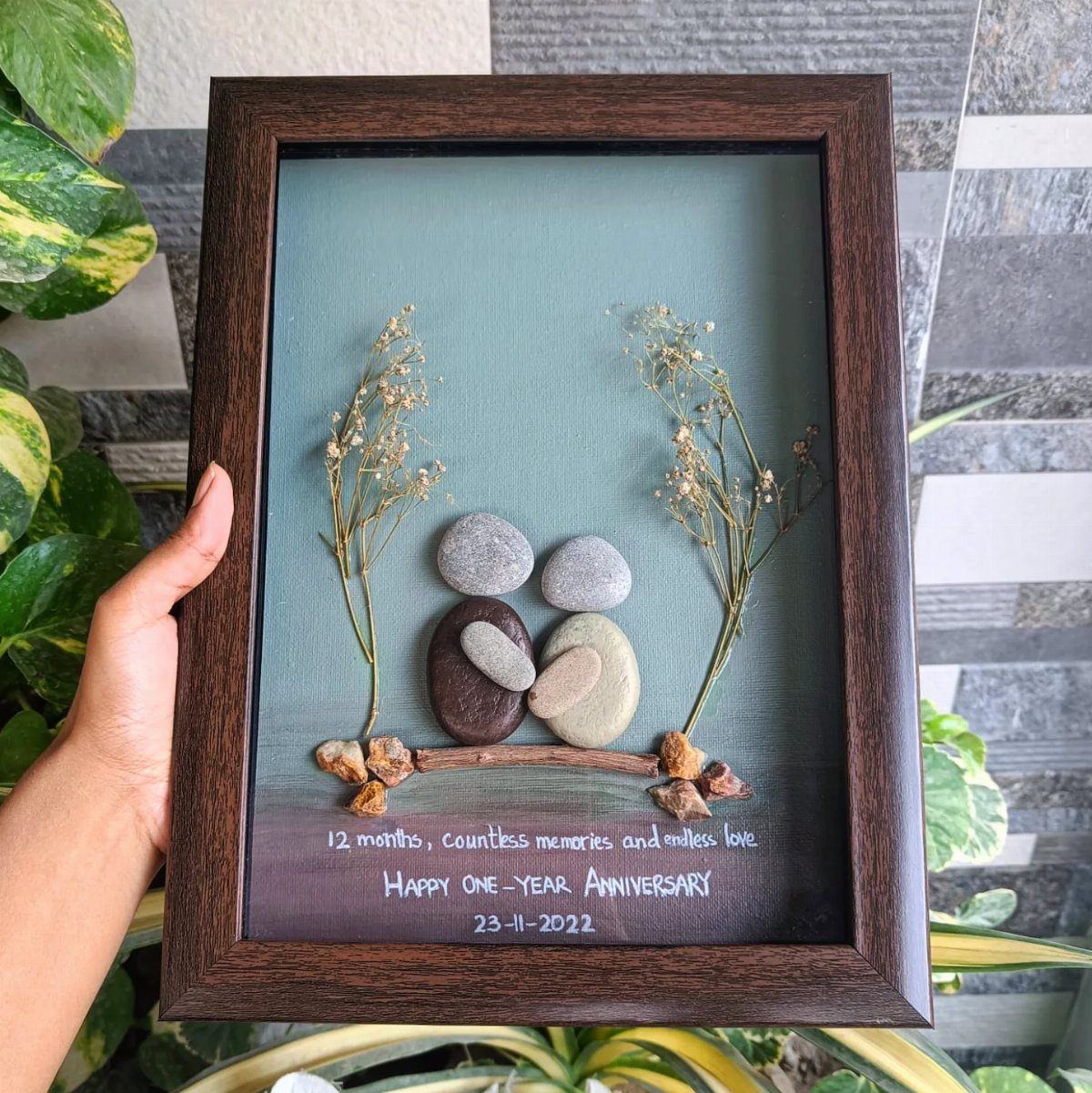 Framed stone art of hugging couples with dried flowers for a first anniversary.