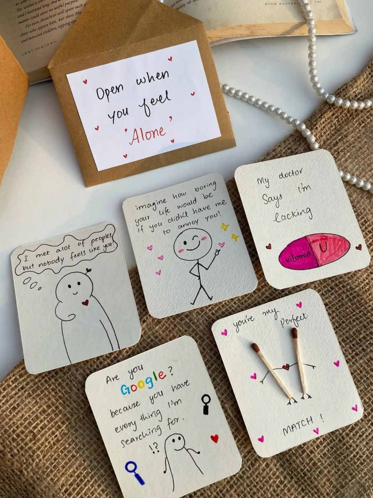 Handwritten love notes with cute drawings and puns on a burlap background.